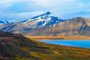 Beautiful scenic view of Blue Gulf under Barren mountain range, with melting snow against the background of a dramatic evening sky, near Baren tsburg, Spitsbergen (Svalbard Island), Norway, Greenland sea.