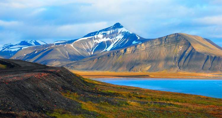 Beautiful scenic view of Blue Gulf under Barren mountain range, with melting snow against the background of a dramatic evening sky, near Baren tsburg, Spitsbergen (Svalbard Island), Norway, Greenland sea. - International Magazine Kreol Beautiful scenic view of Blue Gulf under Barren mountain range, with melting snow against the background of a dramatic evening sky, near Baren tsburg, Spitsbergen (Svalbard Island), Norway, Greenland sea.