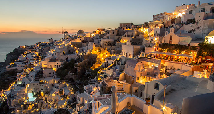 Santorini - International Magazine Kreol Dusk overlooking buildings on the Caldera at Oia Santorini, Greece