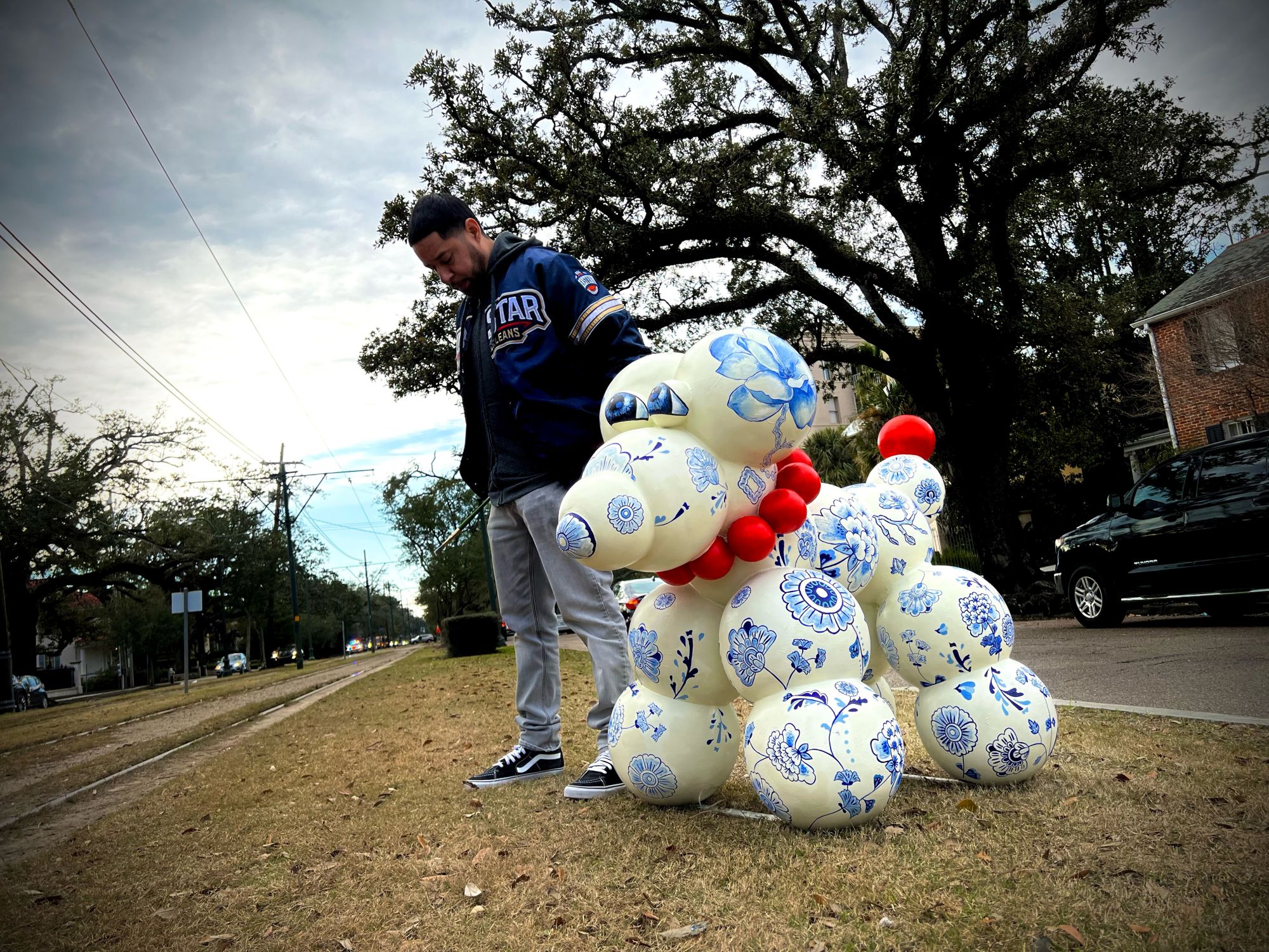 Robert Bocage poses with Sculpture - International Magazine Kreol Robert Bocage poses with Sculpture, Large white dog sculpture with blue decorative patterns